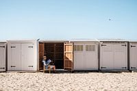 Un homme lit le journal devant une maison de plage