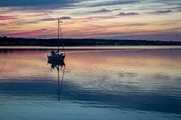 Segelboot bei der Einfahrt in den Hafen von Sydney (Kanada) vor malerischem Sonnenuntergang