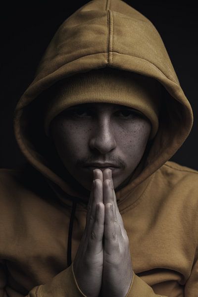 Portrait Young man with hoodie squeezes hands together by Besa Art