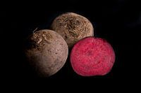 Three red beets on black background