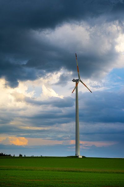 Dramatischer Himmel über einer Windkraftanlage auf der grünen Wiese von adventure-photos