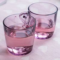 Set of pink tea glasses with liquid for a particularly pink background with white hearts
