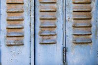 Light blue metal shutters with rusty panels in France