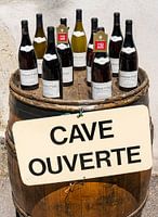 Weinflaschen auf Weinfass mit Schild 'Cave Ouverte'