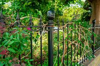 Beautiful dark green fence with flower garden behind it