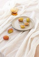 Stillleben mit Pflaumen auf Teller in weichem Licht