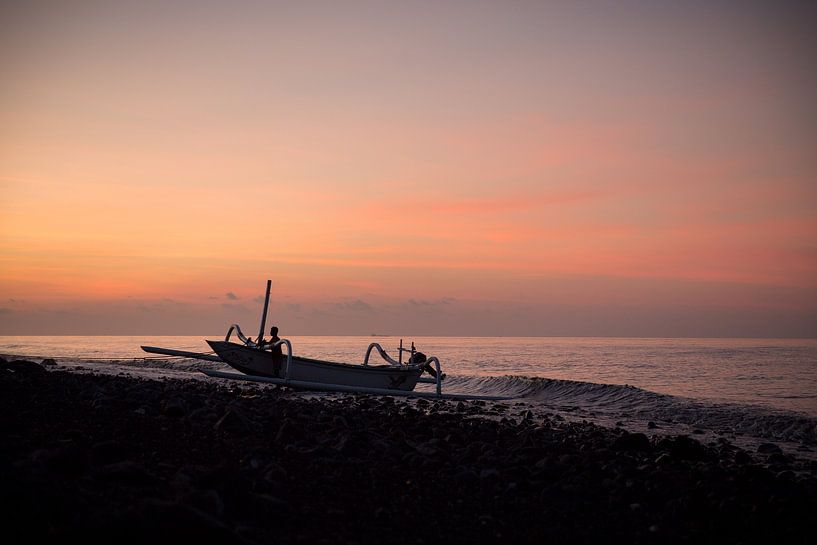 Indonesian fisherman pushing his boat ashore in Kubu, Bali, Indonesia, during sunset. by Esther esbes - kleurrijke reisfotografie