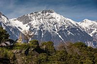 Kleine Steinkapelle vor den verschneiten Bergen