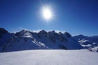 Sonne auf der Skipiste in der Axamer Lizum mit den Kalkkögeln im Hintergrund (Tirol, Österreich)