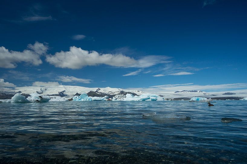 Islande - Eau claire d'un lac glaciaire avec un bateau loin entre les glaces par adventure-photos