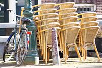 Fahrrad gegen Stange mit gestapelten Stühlen