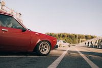 Toyota Corolla rouge oldtimer vue de côté au coucher du soleil