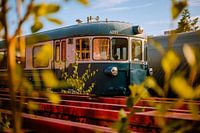 Blauer Vintage‑Triebwagen zwischen roten Schienen – Bahnfotografie zur Goldenen Stunde