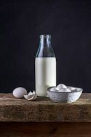 Still life of bottle of milk, eggs on a bench of old oak monastic parts