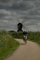 Fietser bij molen met draaiende wieken