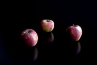 Äpfel spiegeln sich auf einem schwarzen Tisch