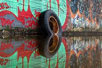 Tyre with a rim reflected in the water.
