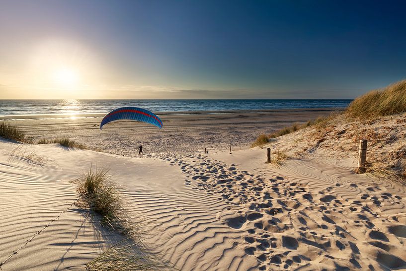 man paragliding on beach at sunset over sea in summer by Olha Rohulya