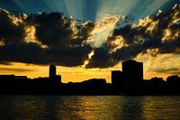 Sunset in Cologne, golden sunbeams, clouds with blue sky city silhouette.