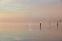 misty sunrise over the water with reflective poles and pastel colors