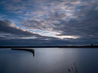 Pfahlreihe im stehenden Wasser bei Sonnenuntergang