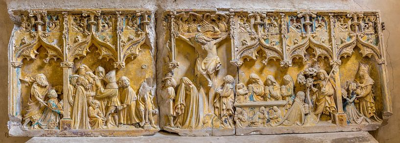Damaged medieval religious stone relief with remains of mainly yellow paint in French church by Joost Adriaanse