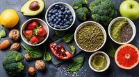 Gezond eten clean eating selectie: fruit, groente, zaden, superfood, granen, bladgroente op grijze kopieerruimte