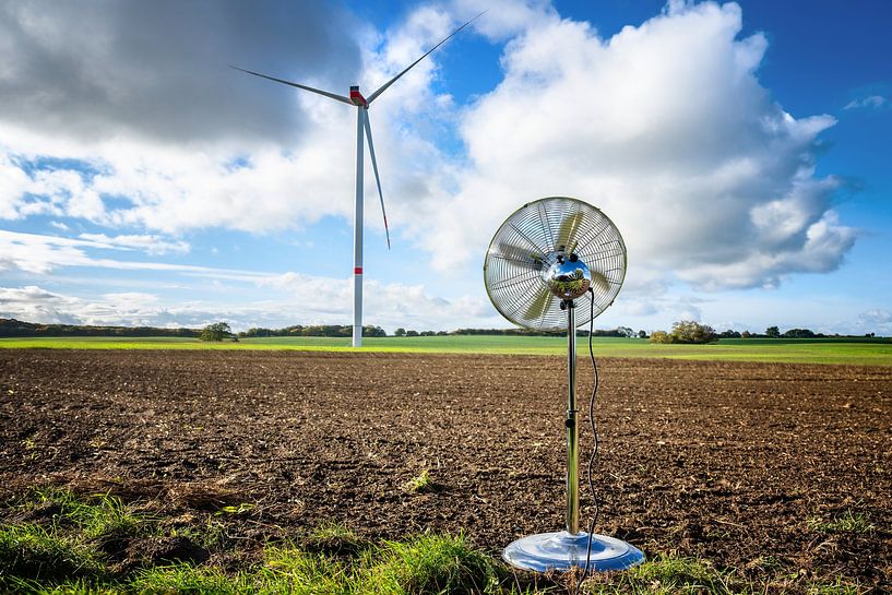 Ventilateur domestique argenté debout sur un terrain devant une éolienne par Maren Winter