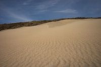 Zandvlakte met blauwe lucht
