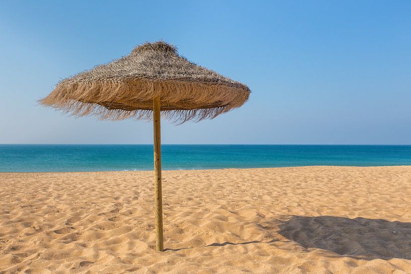 Weidenschirm auf Strand mit blauem Meer und Himmel in Portugal von Ben Schonewille