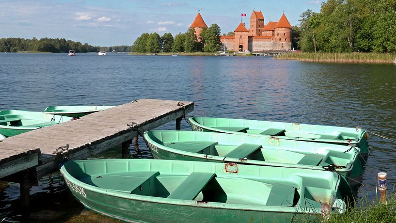 Blick auf die Burg von Trakai mit bunten Ruderbooten auf einem Steg im Vordergrund von Gert Bunt