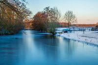 Gefrorener Bach in Winterlandschaft mit Schnee und Herbstfarben