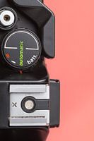 Close up of vintage 'Praktica' camera on bright pink/orange background