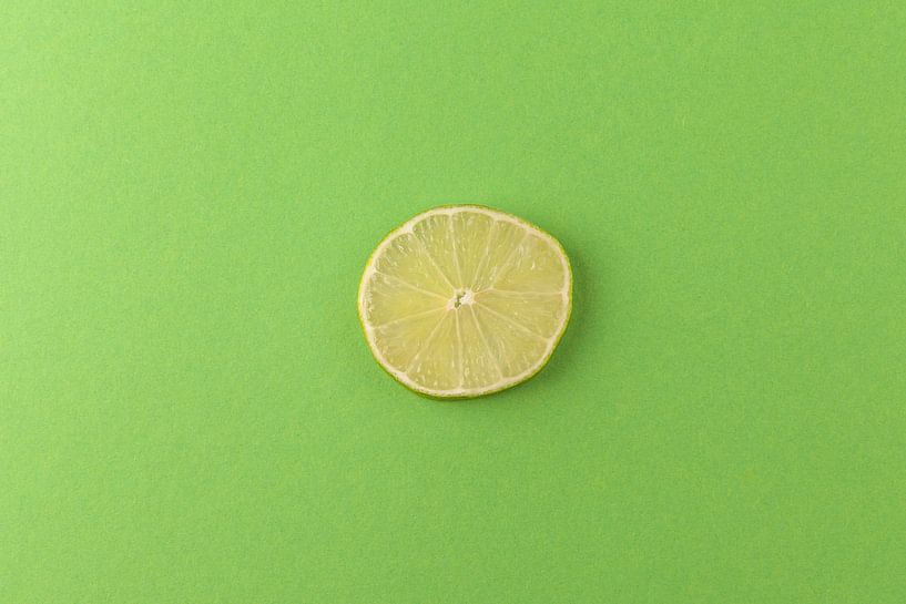Limettenscheibe vor einem grünen Hintergrund von Ans van Heck
