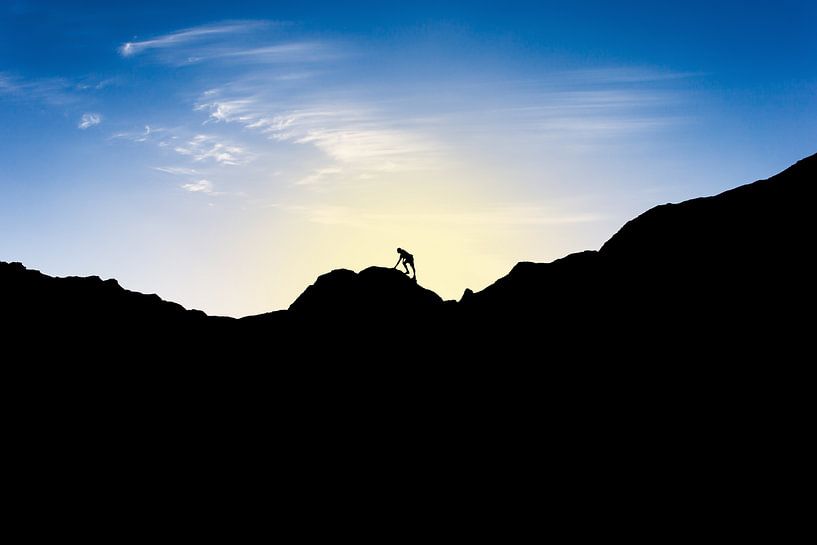 Silhouette of man climbing mountain at sunset. Wout Kok One2expose by Wout Kok