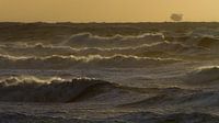 Surf pendant la tempête avec coucher de soleil et plate-forme pétrolière