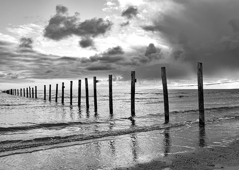 Beach black and white poles in the sea, menacing sky by By Marjolein Design
