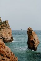 Rochers typiques de l'Algarve avec un voilier au loin