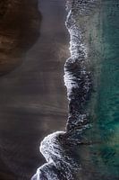 Surfer sur la plage noire