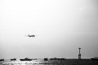 Landend vliegtuig boven zee tijdens zonsondergang High Key