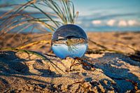 Blick durch die Glaskugel am Strand. Meer und Himmel im Hintergrund