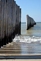 Beach with surf and poles in the sea