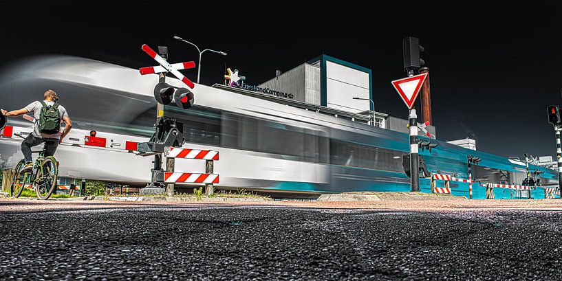 Passage à niveau à Leeuwarden avec un train qui passe à toute vitesse par Harrie Muis
