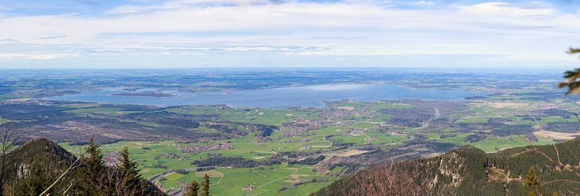 Panoramablick über eine grüne Landschaft mit Bergen im Vordergrund und dem großen Chiemsee in der Ferne von Thomas Heitz