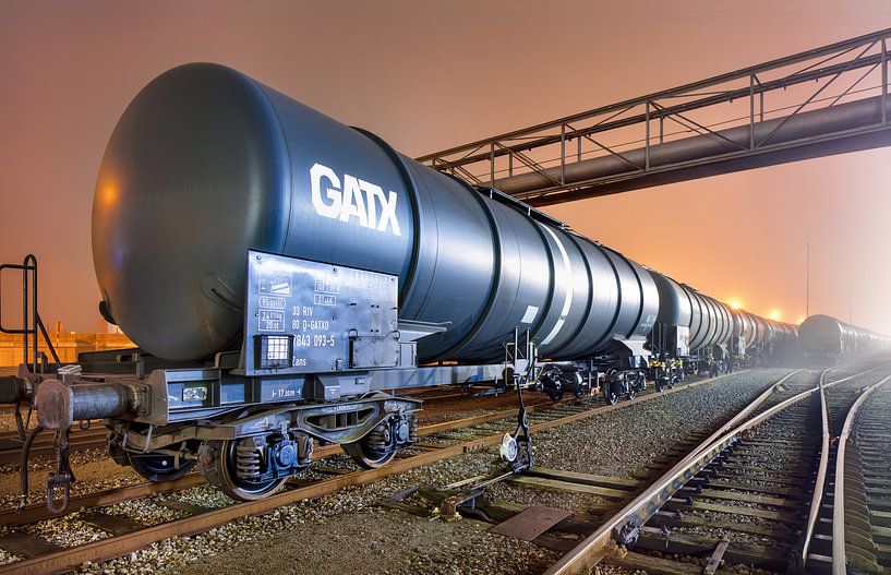 Neblige Nacht Szene mit blauer Schiene Auto gegen orange Himmel von Tony Vingerhoets