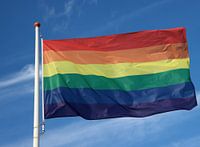 Regenbogenflaggenwellen mit blauem Himmel und Wolken