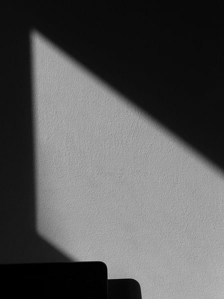 Der Schatten erzeugt eine geometrische Form an der Wand von Natureboi.