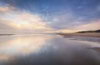 Reflecties op een nat strand bij zonsondergang