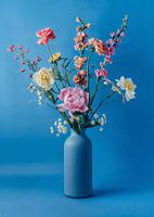 Flower bouquet in blue vase on blue background
