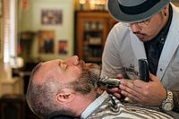A barber trimming a man's beard